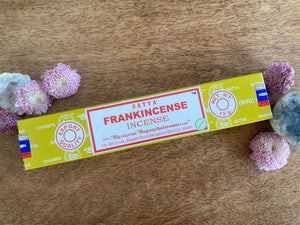 Box of Satya Frankincense Incense on a wooden surface with flowers and crystals.