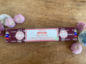 Box of Satya Opium Incense on a wooden surface with flowers around