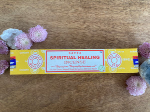 Box of Satya Spiritual Healing Incense on a wooden surface with flowers around